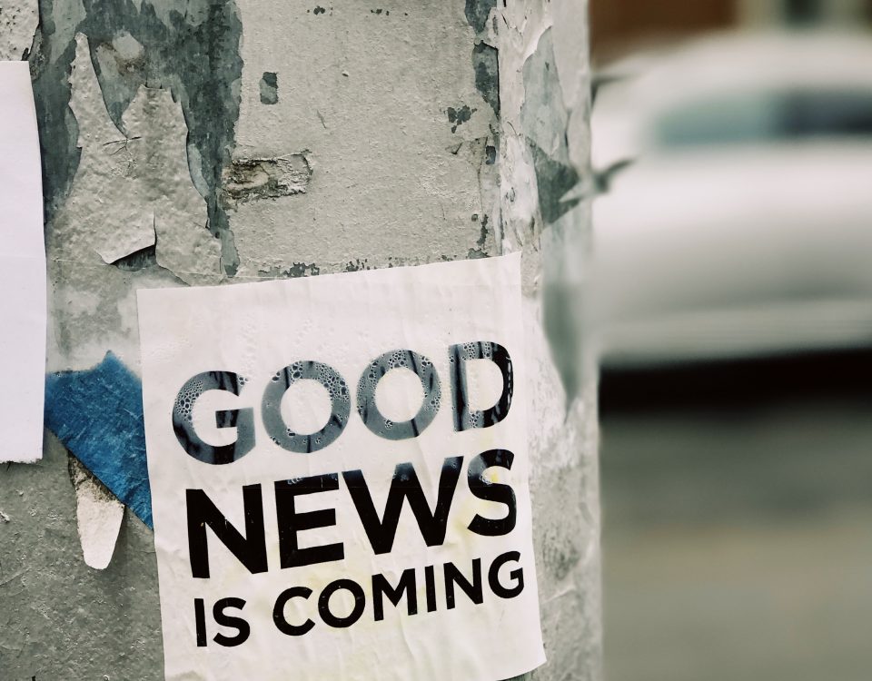 The image depicts a streetlight with a sticker “Good news is coming”.